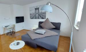 a living room with a blue couch and a lamp at FeelHome Ferienwohnung Tuttlingen in Tuttlingen