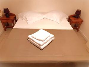 ein Bett mit weißen Handtüchern und zwei Nachttischen in der Unterkunft Manka Anse Mitan in Les Trois-Îlets