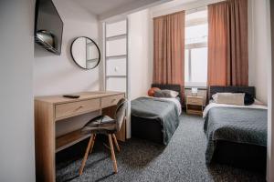 a room with two beds and a desk and a mirror at Piotrkowska Mainstreet & Secure in Łódź