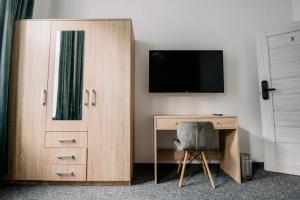 a bedroom with a desk with a tv and a wooden cabinet at Piotrkowska Mainstreet & Secure in Łódź
