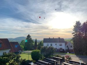 three balloons are flying in the sky over benches at Landhaus Schneeberg AusZeit am Küppel & Bright Collection in Gersfeld +25 photos