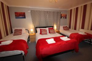 a hotel room with three beds with red sheets at Aspley House in Sutton in Ashfield