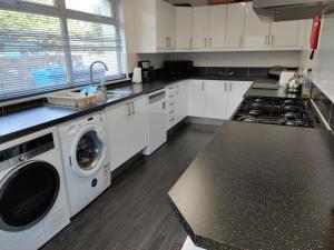 a kitchen with white cabinets and a washer and dryer at Dunvegan House in Helmsdale