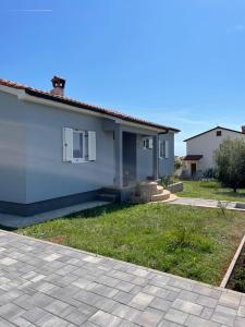 a small white house with a grass yard at Holiday Home Mihaela in Višnjan