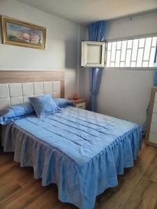 a bedroom with a bed with a blue comforter at Residencial Los Molinos con piscina, TV internacional y Wifi in Playa del Ingles +5 photos
