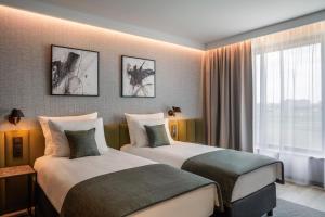 a hotel room with two beds and a window at Q Hotel Plus Wrocław Bielany in Wrocław
