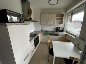 una pequeña cocina con armarios blancos y una mesa en StayHome Apartment Bei Hamburg, en Reinbek