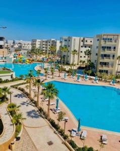 Palm Lake Resort (FOLLA) Sousse-Monastir في المنستير: إطلالة على مسبح كبير مع أشجار النخيل والمباني