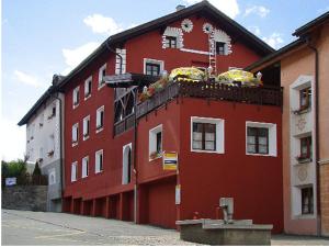 a red building with a balcony on top of it at Crusch Alba in Scuol