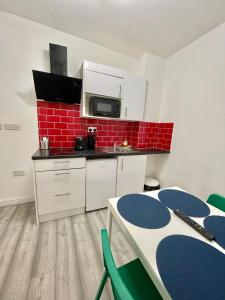 una cocina con armarios blancos y una pared de ladrillo rojo en Comfortable - Cosy - Budget Studios in City Center, en Londres