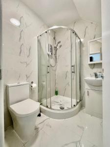 a white bathroom with a shower and a toilet at Comfortable - Cosy - Budget Studios in City Center in London