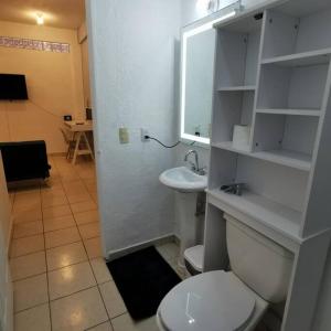 Un baño con un inodoro blanco y un lavabo. en Comfy 2Bedroom minutes from downtown & fast wi-fi, en Zihuatanejo