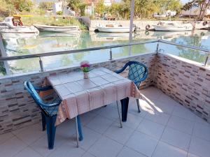 a table and chairs on a balcony with boats in the water at Guest House Ivana in Žvinje