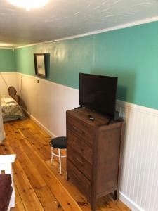 a living room with a television on a dresser with a chair at Seafarer Inn and Cottages in Old Orchard Beach