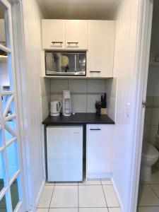 una pequeña cocina con armarios blancos y microondas en Urban Getaway Apartment Ipswich en Ipswich
