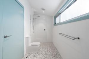 a white bathroom with a toilet and a window at Shelly Beach Holiday Home in Shelly Beach