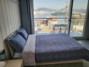 sypialnia z łóżkiem i dużym oknem w obiekcie Yeosu Blooming Pension w mieście Yeosu