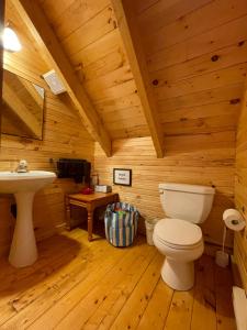 baño con aseo y lavamanos en una cabaña de madera en Avonlea Forest Hill Cottages en New Glasgow