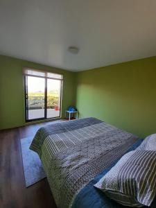 Dormitorio verde con cama y ventana en Casa Pascuala, en Dalcahue