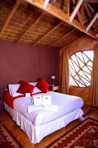 - une chambre dotée d'un grand lit avec des oreillers rouges et blancs dans l'établissement Hotel Poblado Kimal, à San Pedro de Atacama