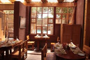 a restaurant with wooden tables and chairs and windows at Hotel Poblado Kimal in San Pedro de Atacama