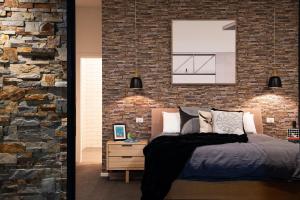 a bedroom with a bed and a brick wall at East St Spa House in Daylesford