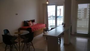 Una sala de estar con un sofá, una mesa y sillas. en Veluvi, en Puerto Madryn