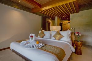 a bedroom with a large white bed with towels on it at Kastara Resort in Ubud