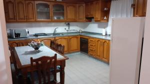 a kitchen with wooden cabinets and a table and a refrigerator at Recanto da Luz in Luz