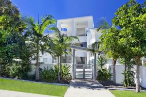 Un edificio blanco con palmeras delante. en 1 Alpha - Lovely and Spacious 3 bed apartment all on one level lift pool air con garden outlook, en Sunshine Beach