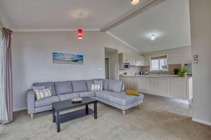 a living room with a couch and a table and a kitchen at Front Row Beachfront in Binalong Bay