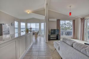 a living room with a couch and a kitchen with a view at Front Row Beachfront in Binalong Bay