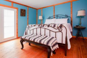 a bed with a bench in a room with blue walls at Coyote Station Lodging in Round Top
