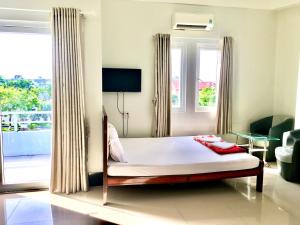 a bedroom with a bed and a large window at Nhà Nghỉ Thiên Minh in Rạch Giá