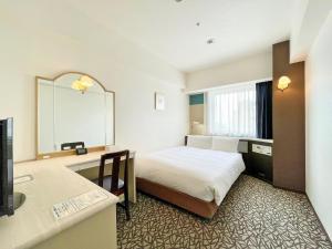 Habitación de hotel con cama y espejo en Chisun Hotel Yokohama Isezakicho, en Yokohama