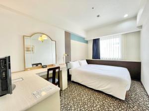 横浜市にあるチサンホテル横浜伊勢佐木町のベッドと鏡が備わるホテルルーム