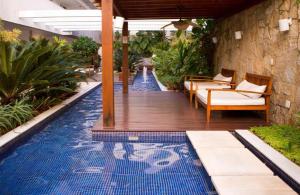 una piscina con sillas y una terraza de madera en Mandai 01 suíte APT 311 MC temporadas en Cabo Frío
