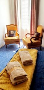 1 Schlafzimmer mit 2 Betten, 2 Stühlen und einem Fenster in der Unterkunft Artistique in Sillé-le-Guillaume