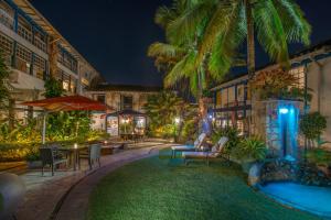 a courtyard with a pool and tables and chairs at night at Sandi Hotel in Paraty