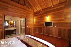 a bedroom with wooden walls and a bed with a television at Ye Jiang Hua Homestay in Meishan