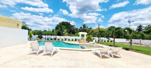 - une piscine avec quatre chaises et une piscine dans l'établissement Hotel Quinta Izamal, à Izamal