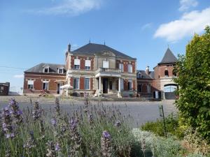 a large brick house with purple flowers in front of it at Ferme De Bonavis in Banteux