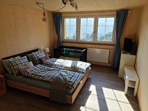 a bedroom with a bed and a desk and windows at Grosses Ferienhaus für traumhafte Familienferien im Appenzellerland in Speicher