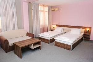 a hotel room with two beds and a chair at Hotel Tundzha - Renovated! in Yambol