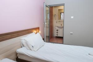 a bedroom with a large white bed with a mirror at Hotel Tundzha - Renovated! in Yambol