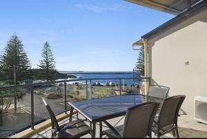 a balcony with a table and chairs and a view of the ocean at The Cove Yamba in Yamba