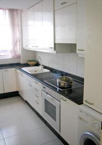 a kitchen with white cabinets and a sink and a stove at Apartamento en La Toja de tres habitaciones in O Grove