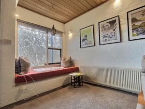 a room with a window with a red bench and a table at Snow Gums Apartment 4, alpine-getaways in Dinner Plain