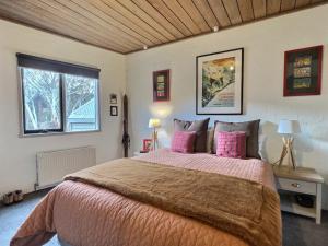 a bedroom with a large bed with pink pillows at Snow Gums Apartment 4, alpine-getaways in Dinner Plain