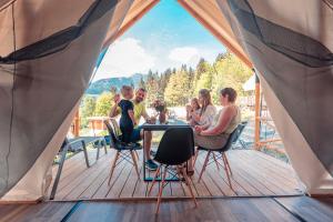 a group of people sitting around a table in a tent at Chalets & Glamping Nassfeld by ALPS RESORTS in Kötschach